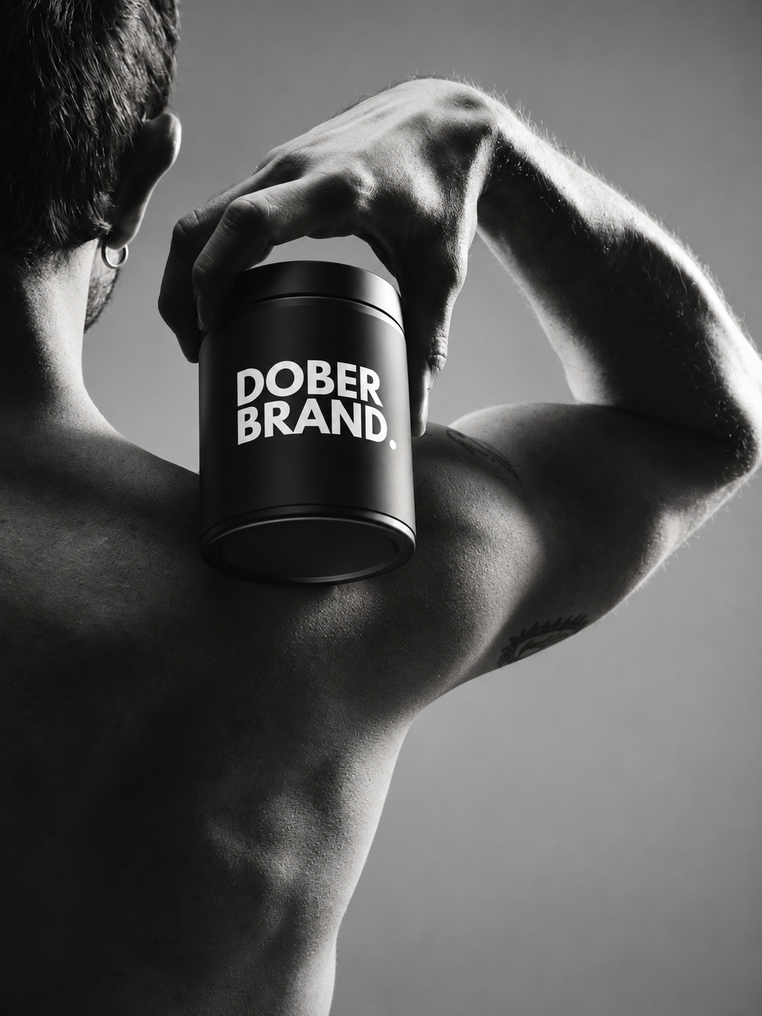 Atleta sosteniendo un suplemento DOBERBRAND en una campaña editorial en blanco y negro
